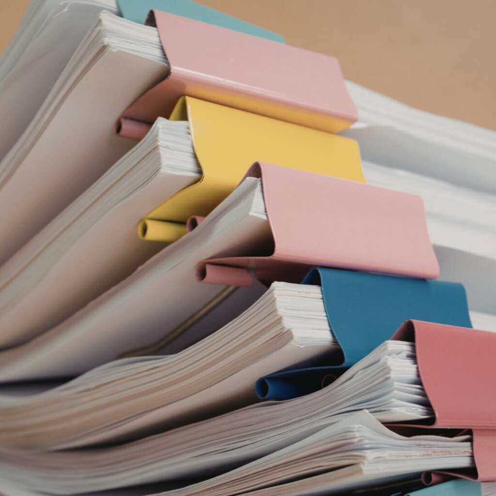 Neatly stacked paperwork with labeled tabs for debt collection framework. 
