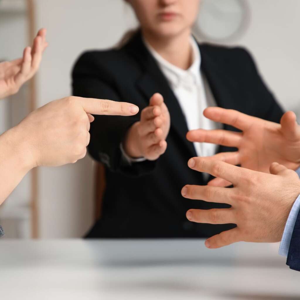 Lawyer putting up a hand between two clients, but body language turned slightly away from both